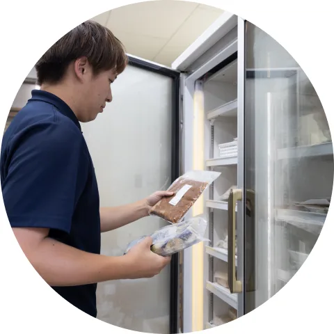 冷凍庫に食品を収納する伊鈴屋のスタッフ